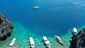 Luchtfoto van traditionele boten in een donkere lagune omringd door kalkstenen eilanden bij Coron op Palawan