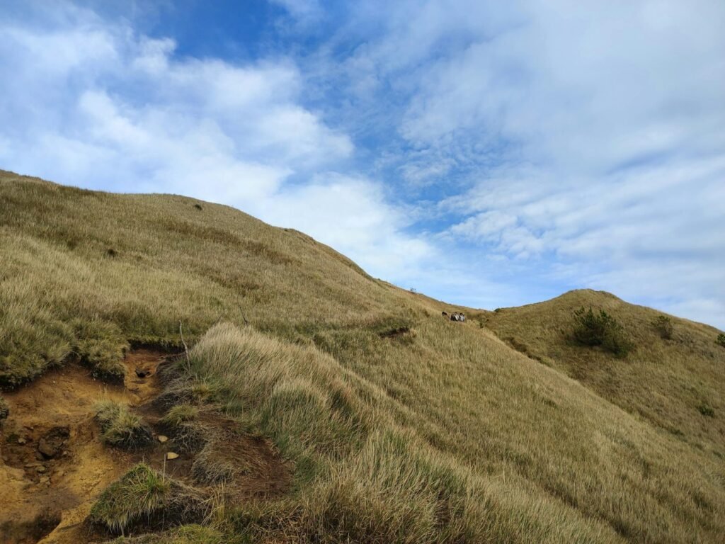 Breed bergpanorama van Bukidnon met groene heuvels, valleien en wolken boven de bergen.