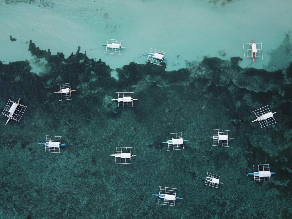 Dronefoto van traditionele boten in helder water bij Moalboal, Cebu.
