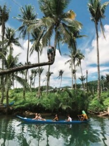 Mensen in een kano onder hoge palmbomen op een tropische rivier op Siargao.