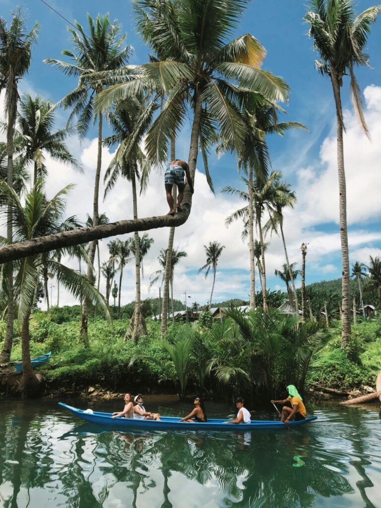Mensen in een kano onder hoge palmbomen op een tropische rivier op Siargao.