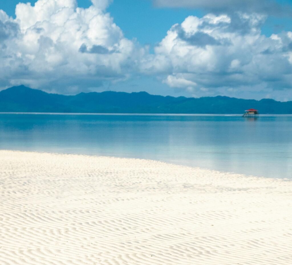 Wit zandstrand met kalm water en bergen op de achtergrond op Siargao.